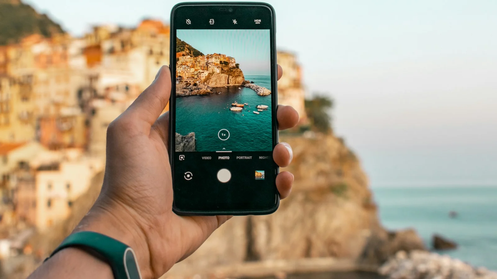 Hand holding a phone photographing a coastal village