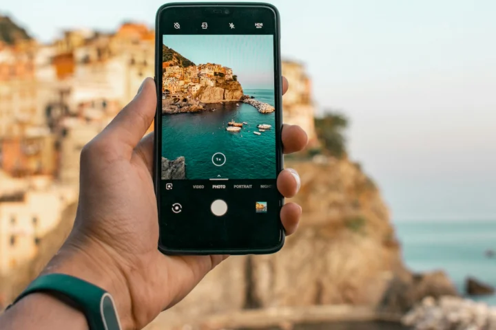 Hand holding a phone photographing a coastal village
