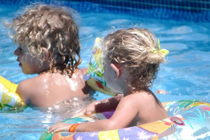 Two small children playing in a pool with floats