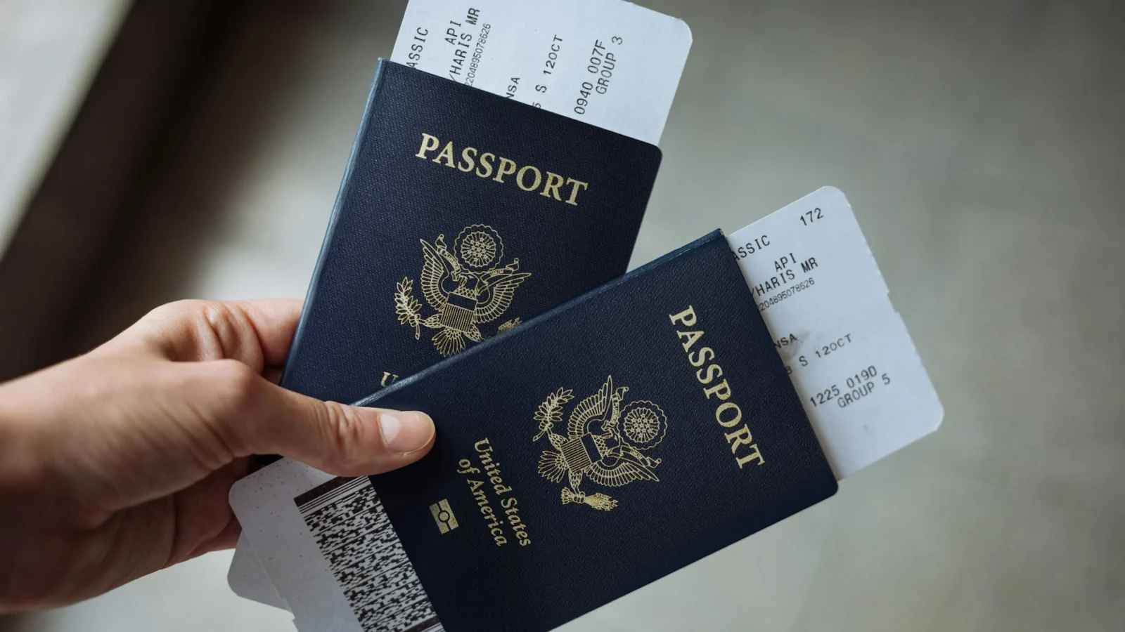 Hand holding two US passports with boarding passes