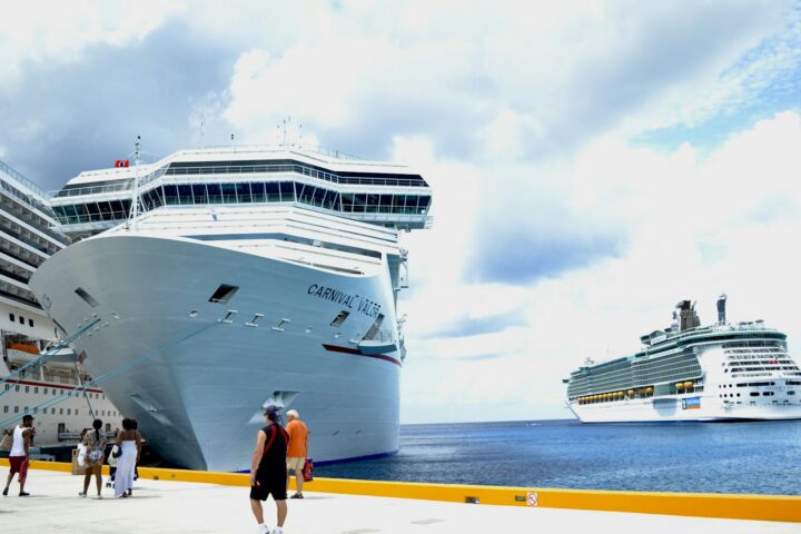 Passengers walking along a pier beside Carnival Valor