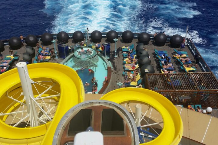 Yellow waterslides and a pool deck on a cruise ship seen from above