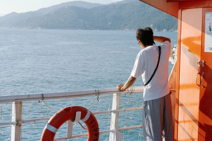 Traveler alone at the ship railing looking at the coast