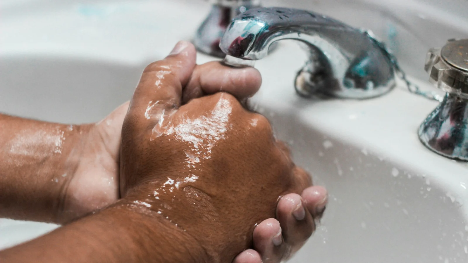 Hands being washed with soap under a running tap