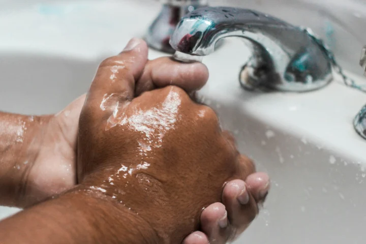 Hands being washed with soap under a running tap
